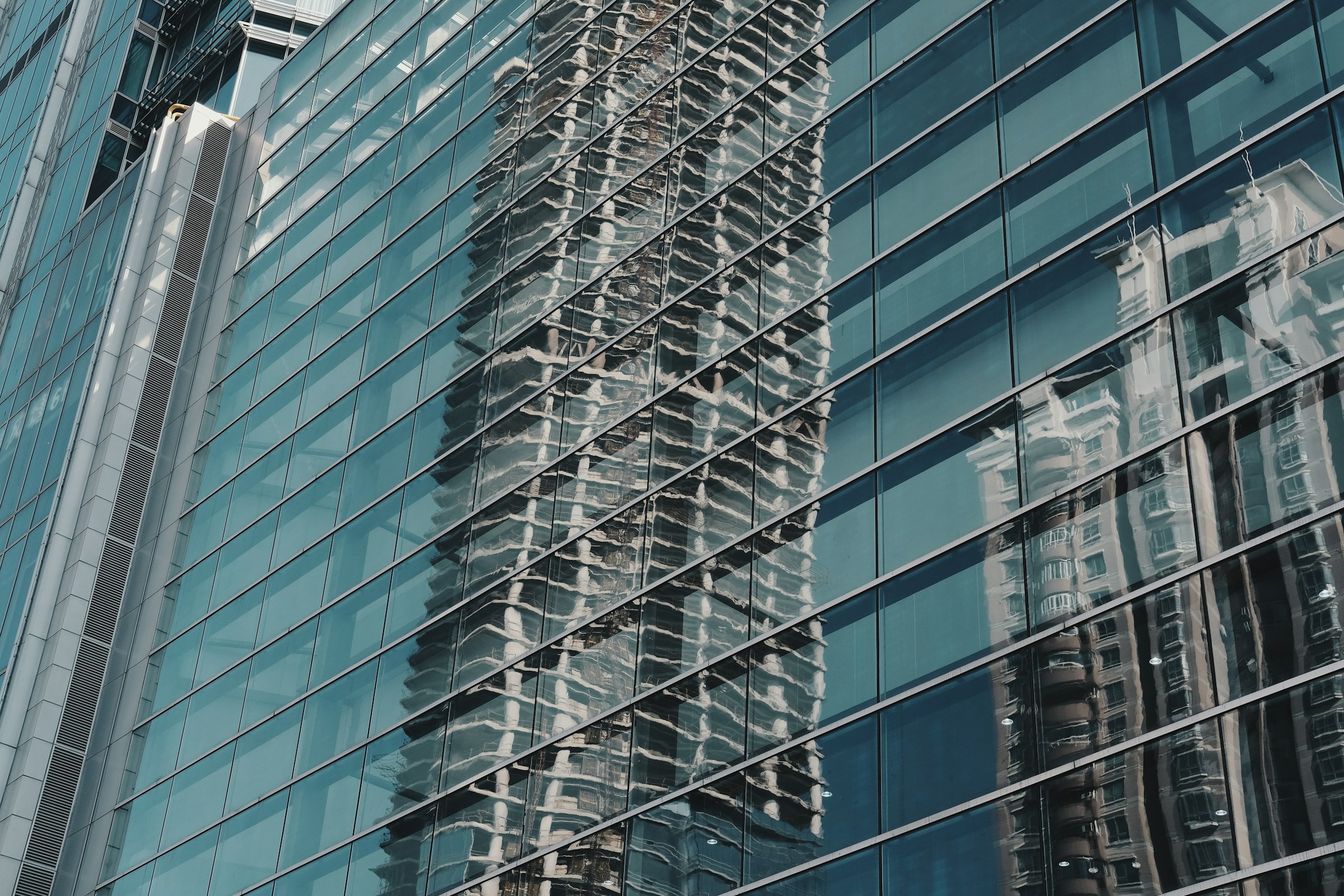 Reflective glass curtain wall with aluminum framing and reflections of adjacent buildings