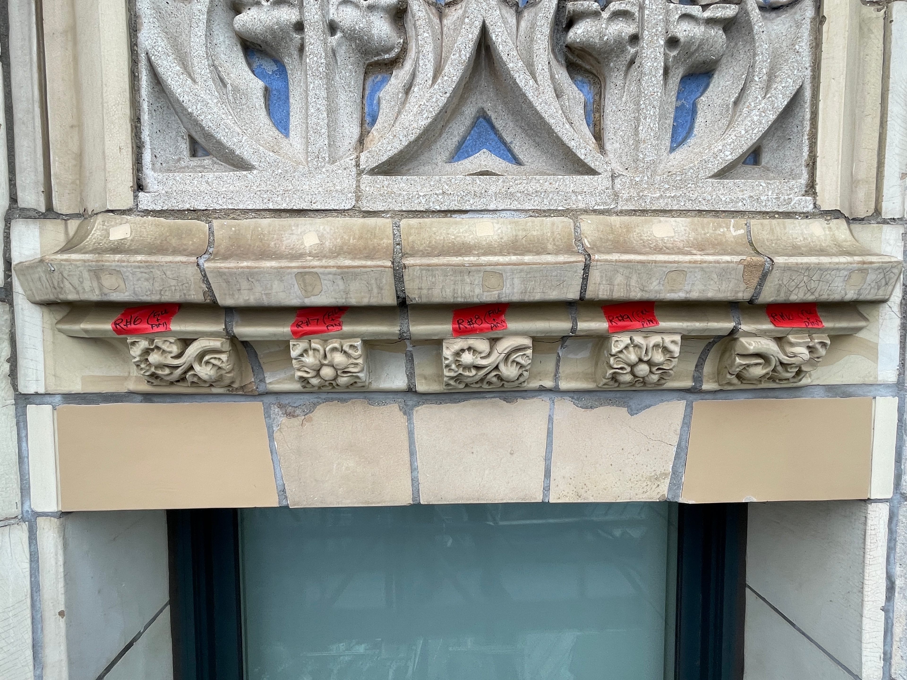 Historic terra cotta facade with marked repair locations and architectural ornament