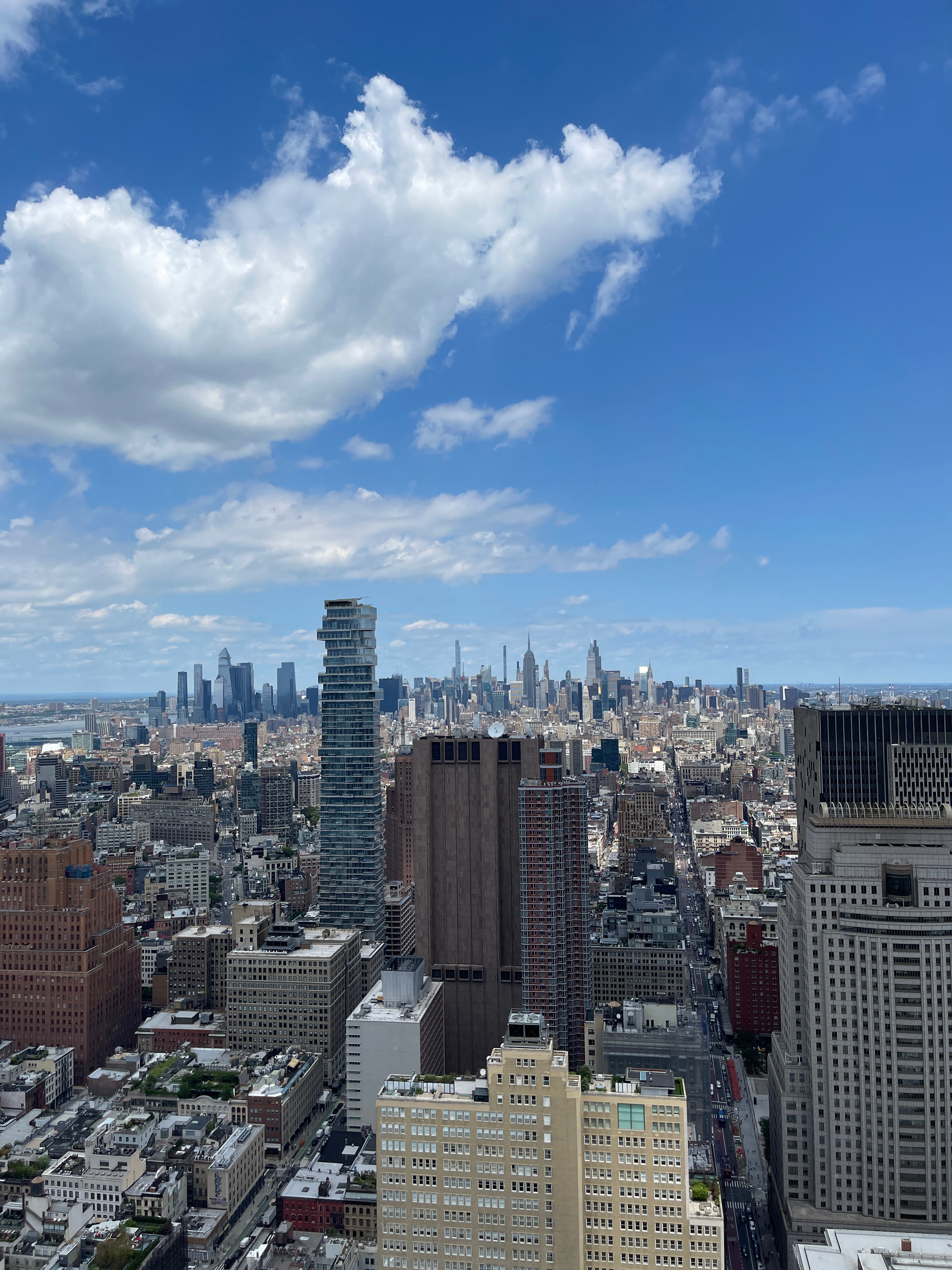 Manhattan skyline and existing buildings beneath a blue sky with white clouds