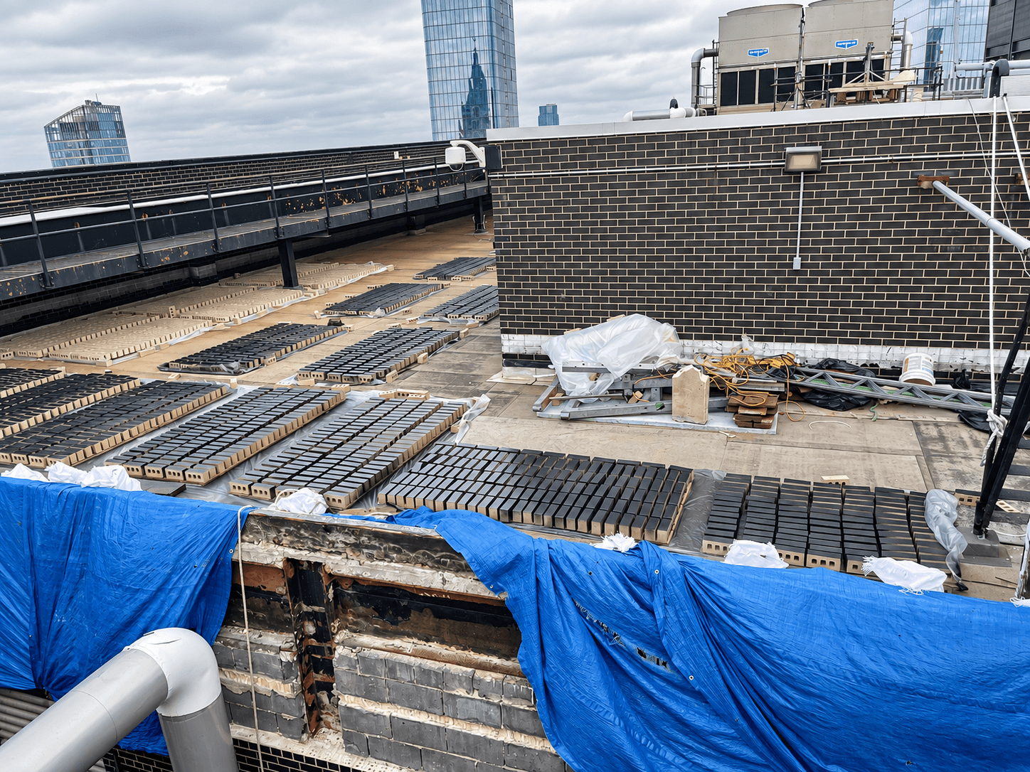 Rooftop construction area with staged masonry materials, equipment and protected work zones